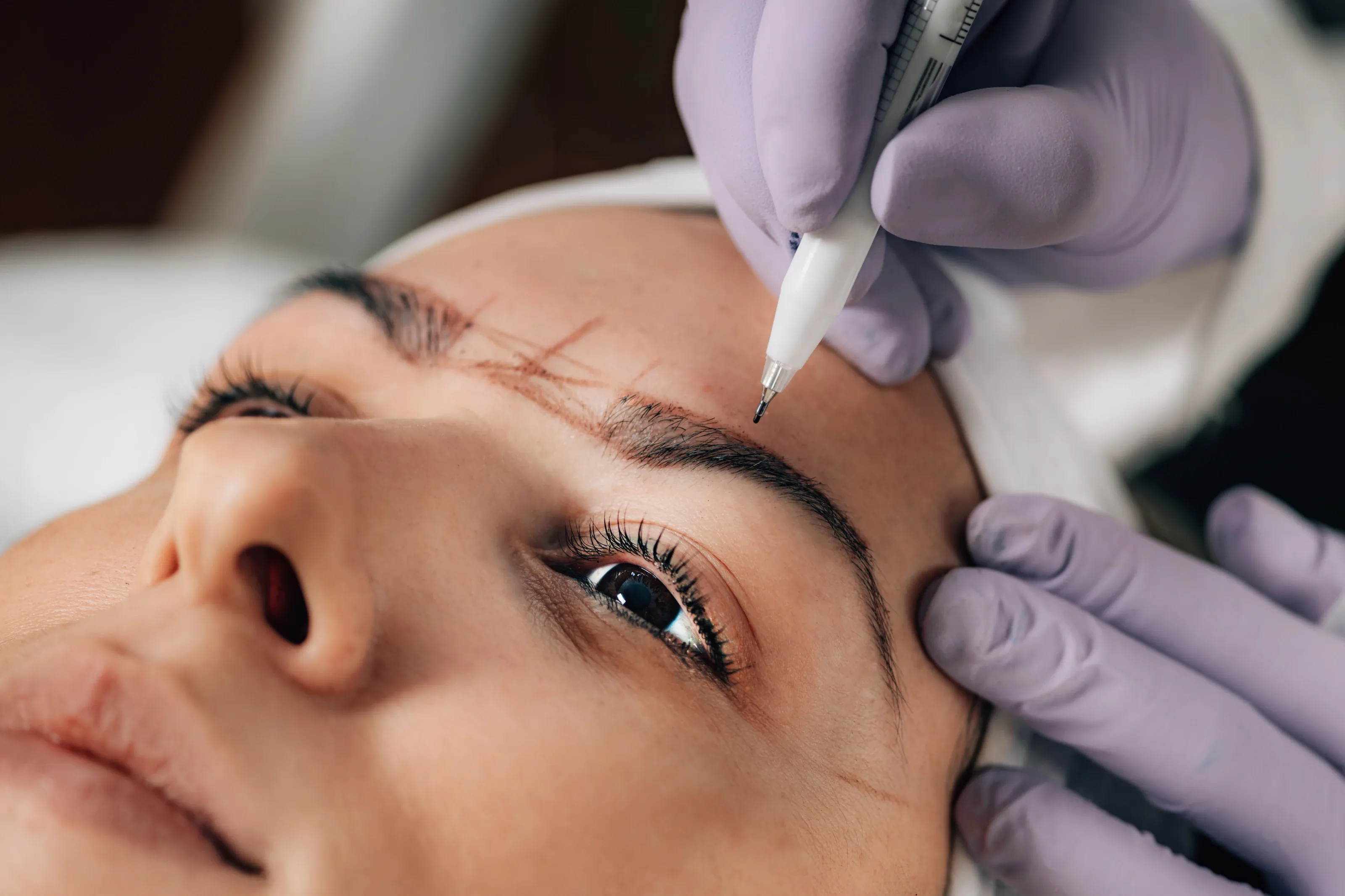 Brow being marked out with a pen on a client's face before semi-permanent makeup